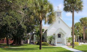 Picture of melbourne beach chapel, an all-white building with a steeple and trees in the front yard