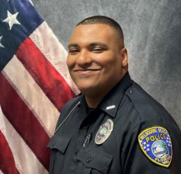 Officer Luis Tejeda in front of American Flag.