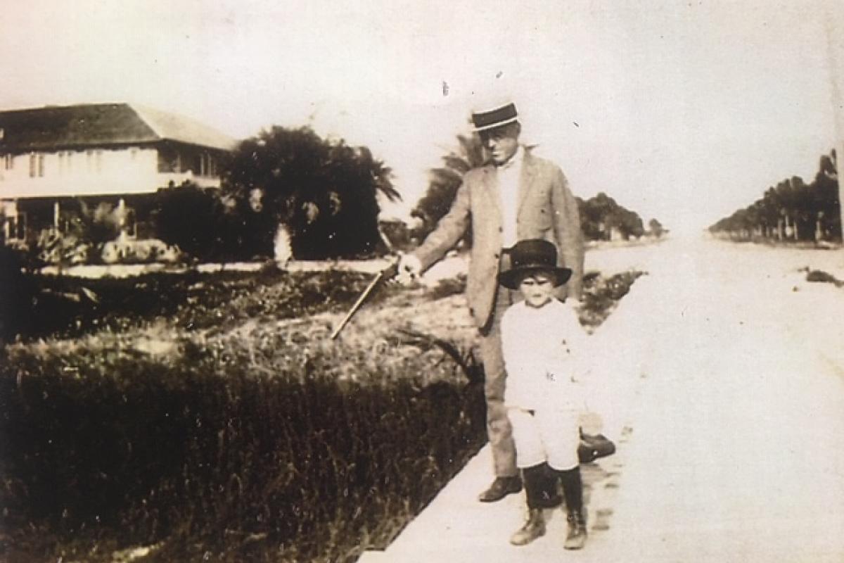 historical photo of a man with a gun and child by the river