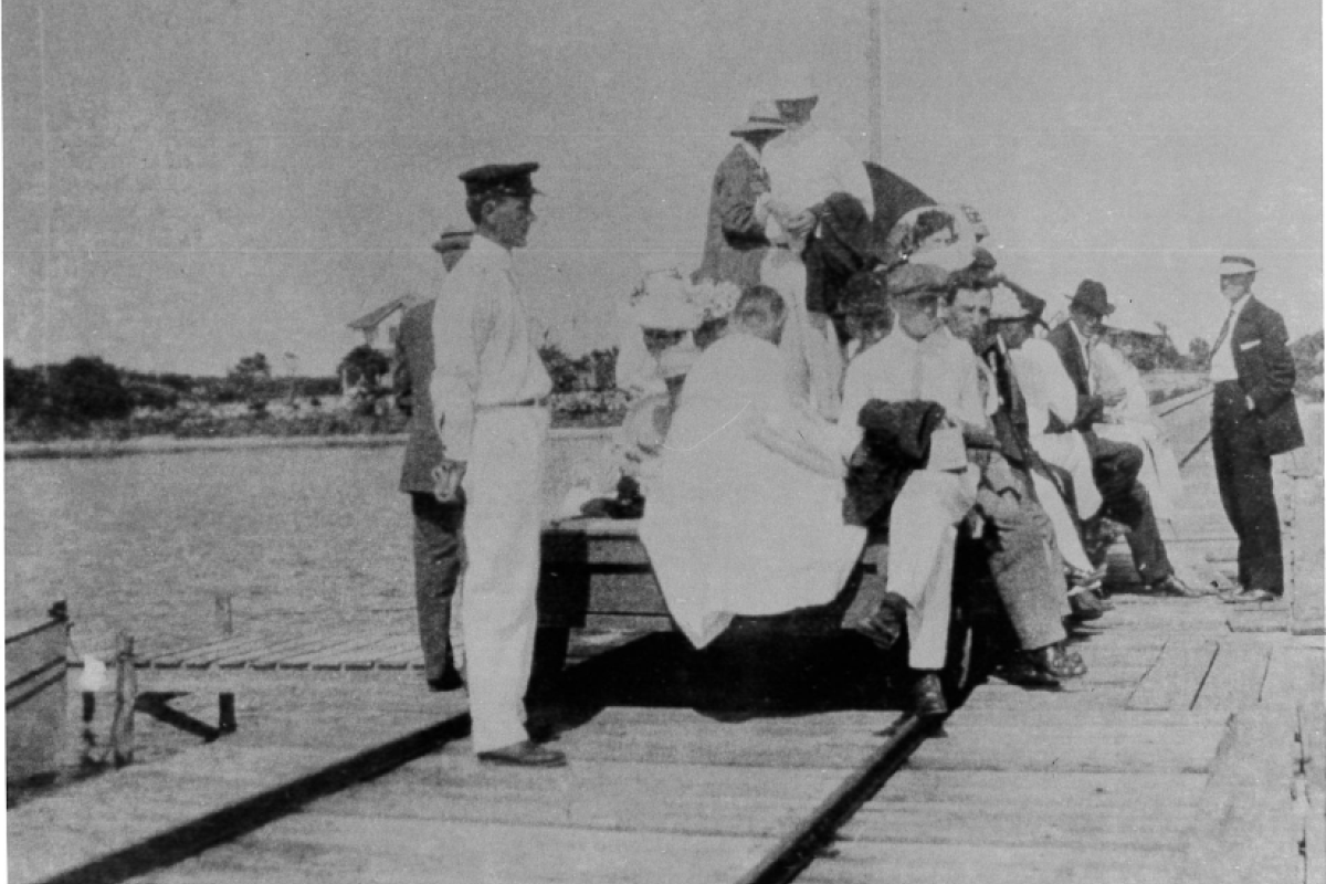 historical photo of men and women on a push car on the pier